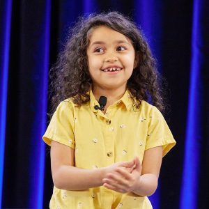 Eliana Fernandez in a yellow shirt with flowers speaking