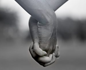 grayscale photo of two person holding hands